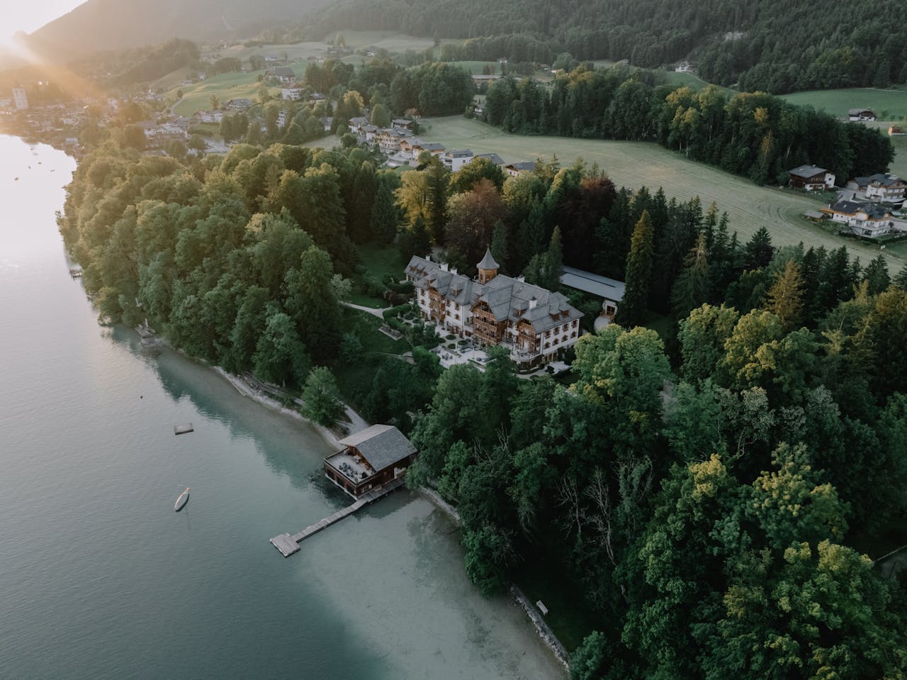 Aerial view of a majestic lakeside mansion in Salzburg, Austria during sunset.